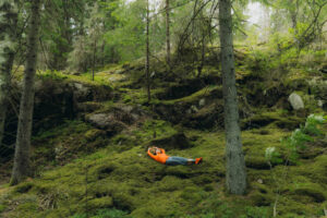 woman contemplating nature of sweden relaxing on moss in the forest - dennenbos stockfoto's en -beelden